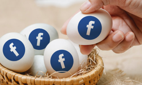 Hand placing an egg with a Facebook logo on it in a basket